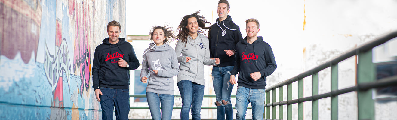 Das Zurfday Team läuft lachend auf den Fotografen zu, alle tragen Hoodies von Zurfday