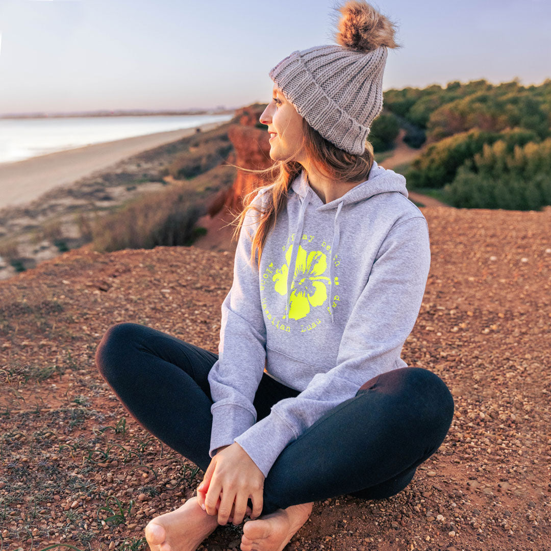 Junge Frau sitzt am Meer und blikt aufs Wasser, sie trägt einen Zurfday Hoodie