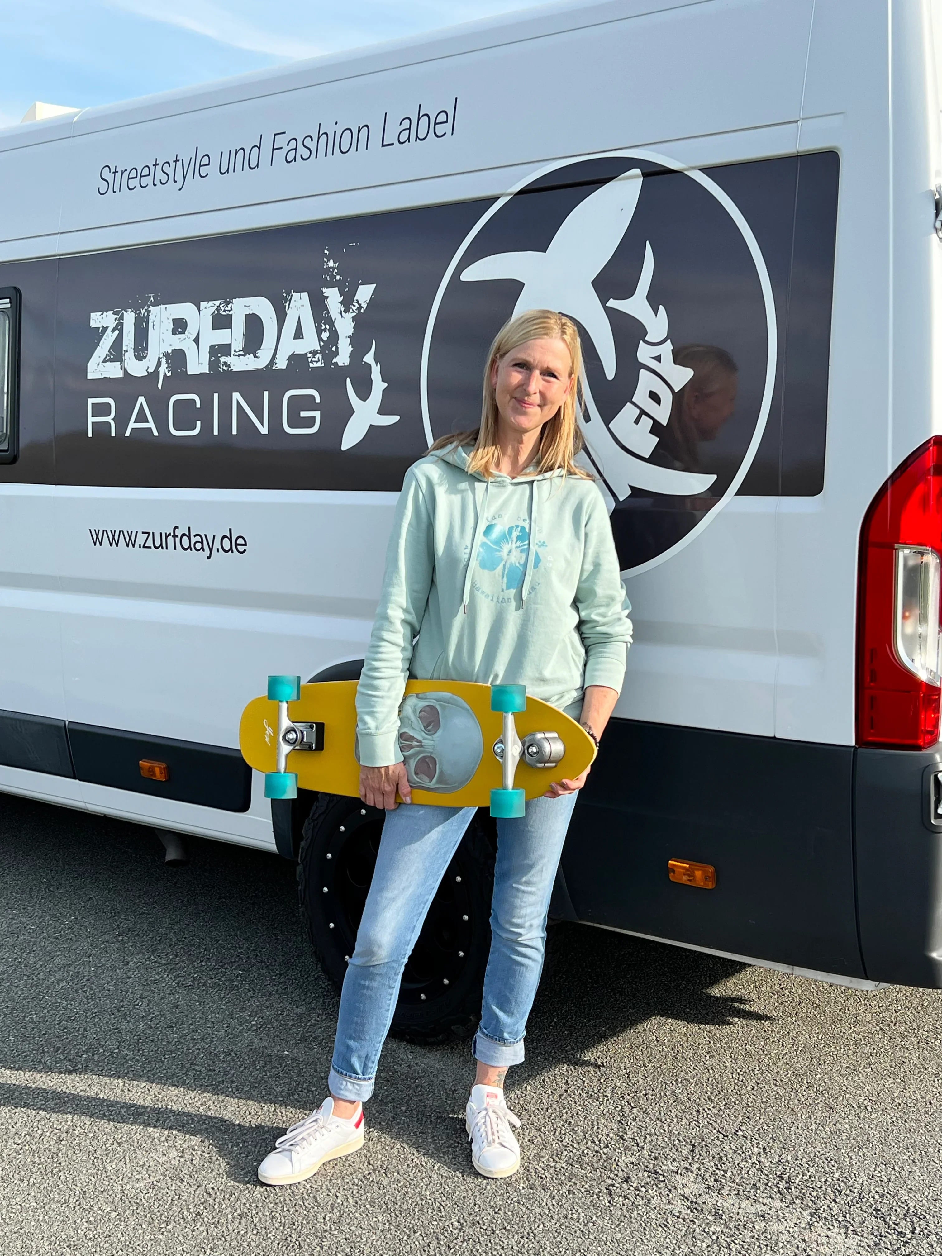 Kristine im Zurfday-Look und mit gelben Skateboard.