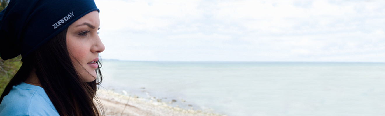 eine junge Frau steht am Strand und trägt eine Benie Mütze von Zurfday