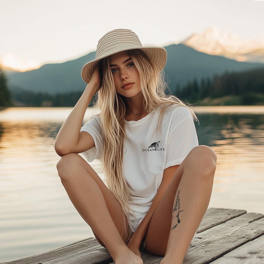 Junge Frau sitzt am See und trägt das Ocean Life T-Shirt von Zurfday