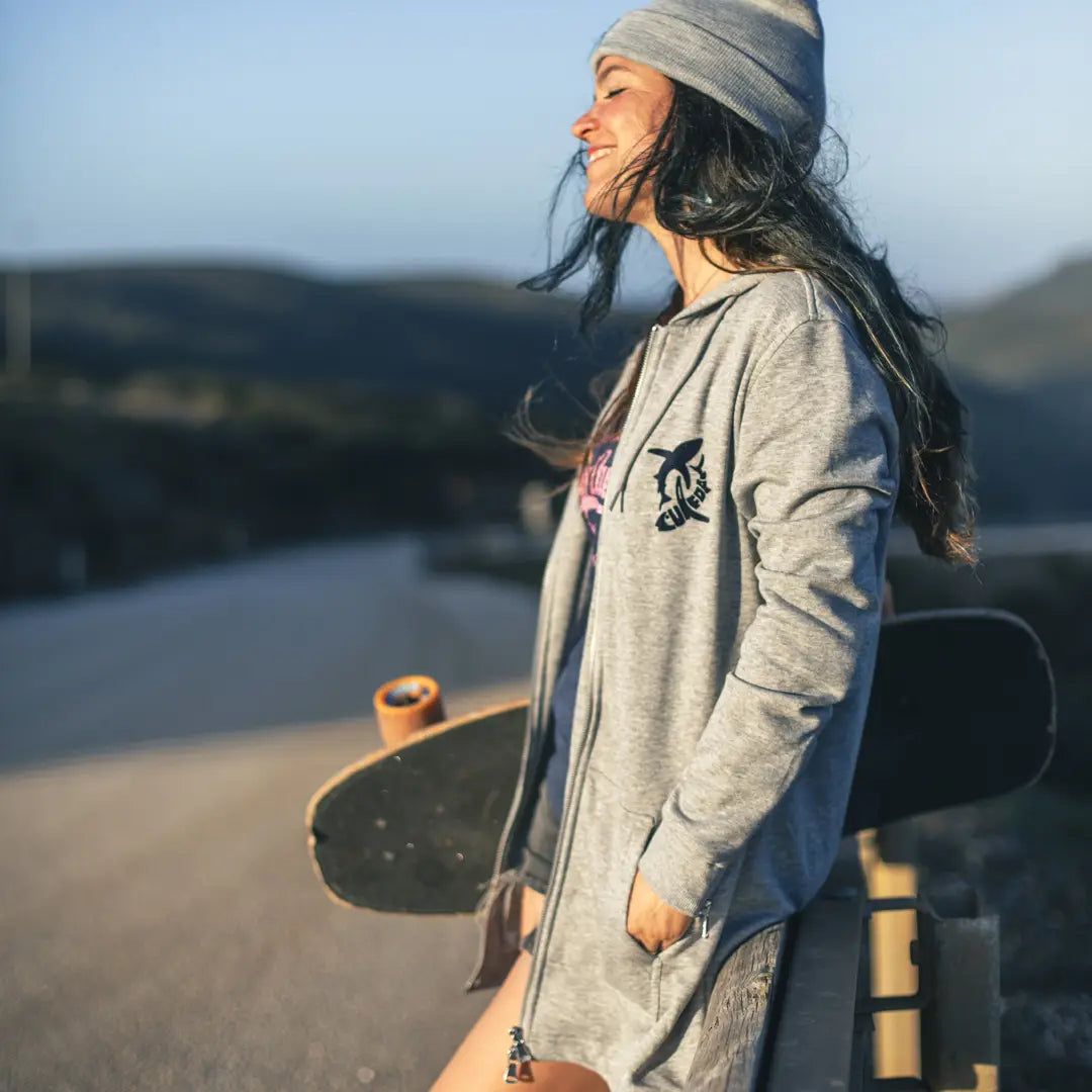 Junge Frau mit Skateboard schaut entspannt in die Sonne