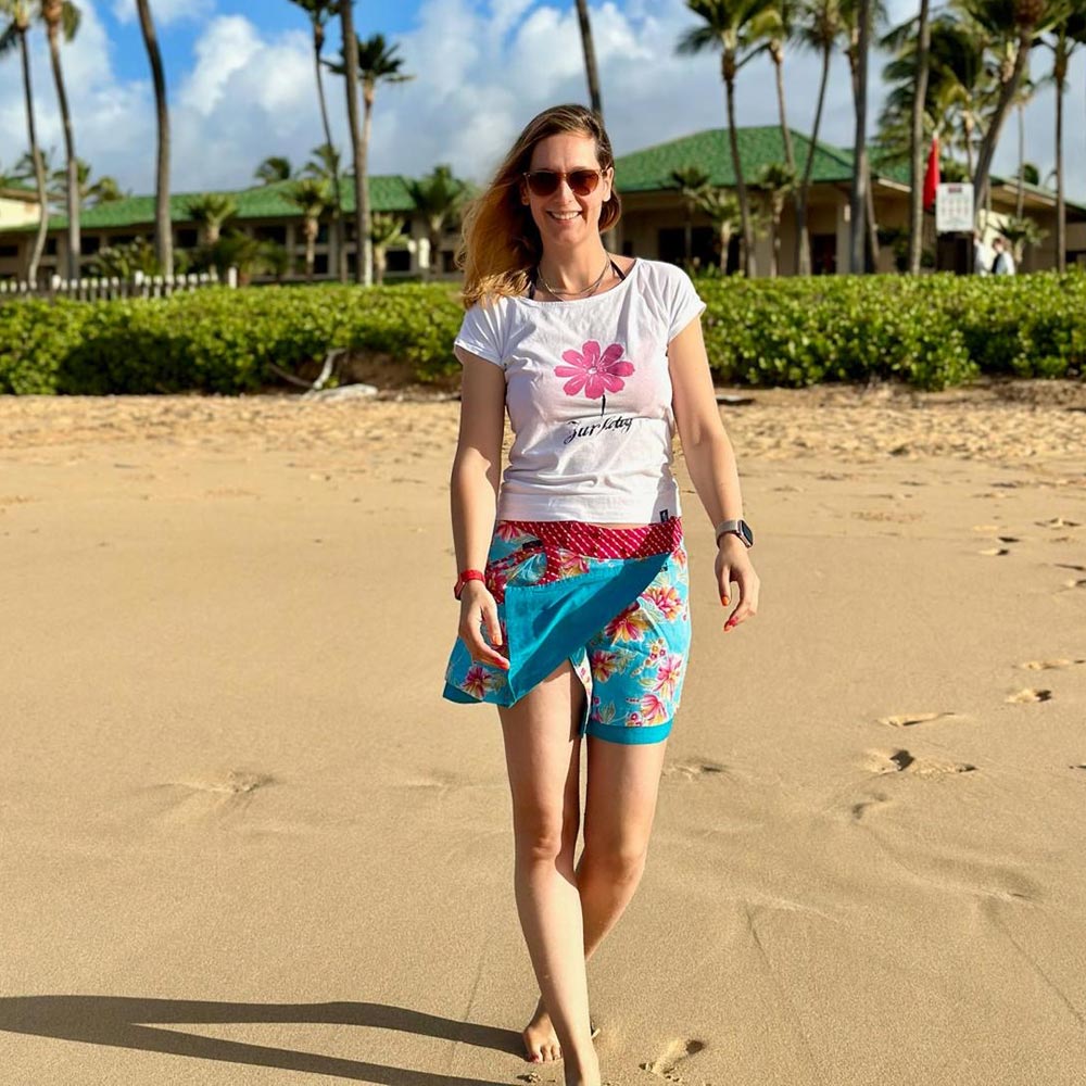 Eine junge Frau steht lachend am Strand und trägt einen Zurfday Rock