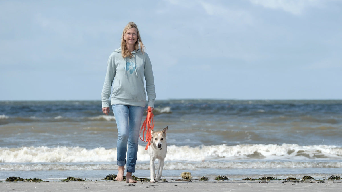 Kristine, Gründerin von Zurfday mit Hündin Zoe am Strand.