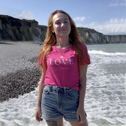 junge Frau am Meer mit geschlossen Augen, trägt ein zurfday T-Shirt in Pink